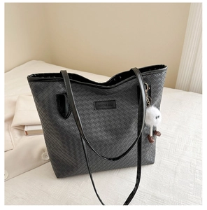 Détail de la texture tissée du grand sac cabas noir avec pendentif peluche à yeux