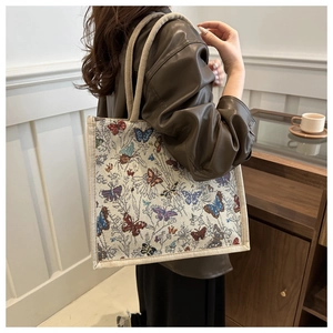 Detail of vintage canvas tote bag featuring colorful butterfly patterns and woven handles
