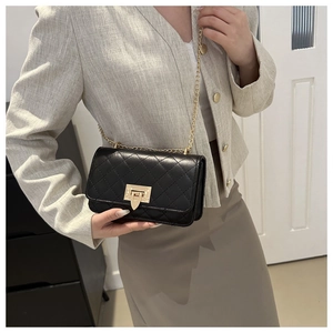 Détail du sac bandoulière en cuir matelassé noir avec chaîne dorée sur le mannequin