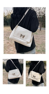 Close-up of minimalist beige shoulder bag featuring a metal bow and chain strap