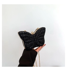 Macro shot of butterfly-shaped glitter clutch bag with gold chain and diamond clasp