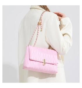 Detail of pink quilted chain bag with gold lock worn over a white suit blazer