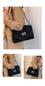 Detailed view of matte black shoulder bag with silver bow buckle and chain strap detail
