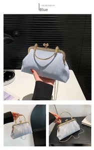 Close-up of light blue kiss-lock bag with gold ring handle and pleated texture fabric
