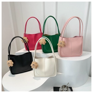 Group display of chic tote bags in five colors with cute plush bear charms on white steps