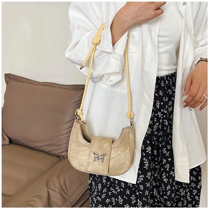 Détail d'un sac demi-lune kaki avec boucle papillon argentée et fine bandoulière jaune