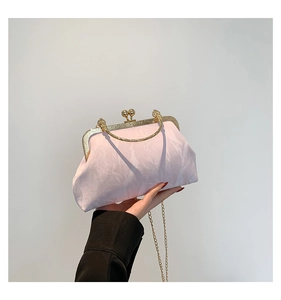Macro detail of elegant pink pleated clutch bag with gold metallic ball clasp and chain