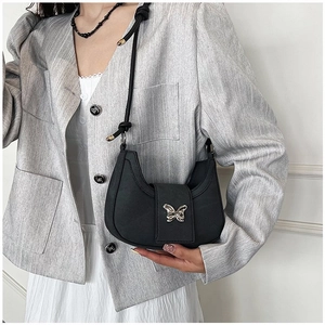 Sac à bandoulière demi-lune noir minimaliste avec papillon argenté porté par un modèle
