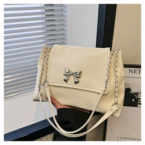 Detailed shot of cream PU leather handbag featuring a silver metal bow buckle and chain strap