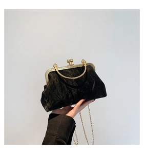Detail of vintage black pleated fabric evening bag with ornate gold metal frame and handle
