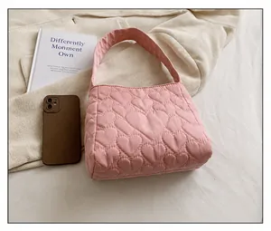 Close-up of pink quilted tote bag with heart patterns on soft fabric and top handle