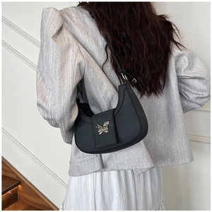 Détail du sac hobo noir avec boucle papillon en métal argenté sur cuir texturé