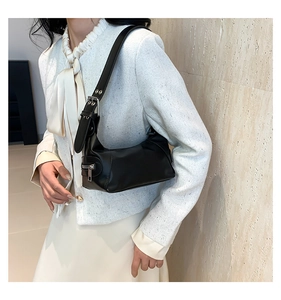 Detail of minimalist black underarm bag with silver square buckle and smooth faux leather