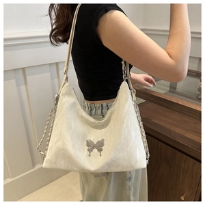 Dettaglio borsa a spalla bianca plissettata con decorazione farfalla in argento e catenella