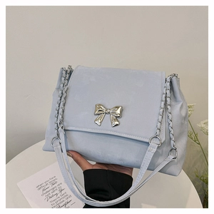 Detail shot of light blue suede shoulder bag with silver bow buckle and chain strap