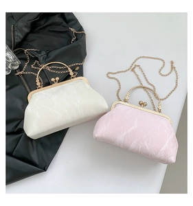 Detail view of stylish white and pink pleated bags with golden metal handles and chains