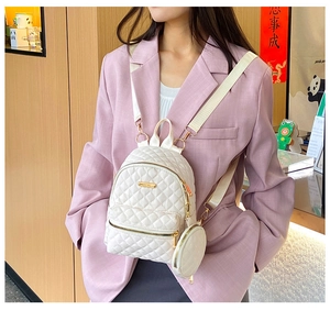Close-up of a white quilted mini backpack with matching coin purse and gold hardware detail