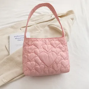 Detail of pink quilted tote bag showing padded heart patterns and soft nylon texture