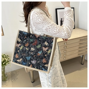 Detail of vintage butterfly tapestry tote bag with woven handles on white crochet dress