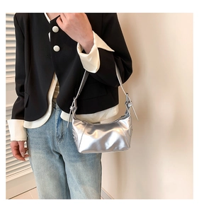 Detail of silver metallic hobo shoulder bag with adjustable buckles on black suit