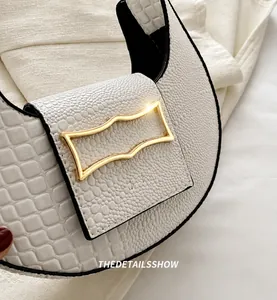 Détail du sac demi-lune blanc à motif crocodile avec une boucle en métal doré