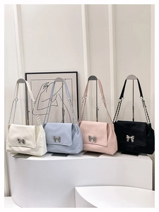 Detail showing four colors of shoulder bags with metal bow accent and chain straps
