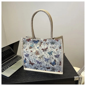 Detailed view of cream canvas tote bag featuring vintage colorful butterfly prints and rope handles