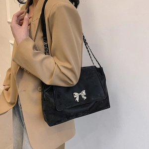 Elegant black suede shoulder bag with silver bow accent and metal chain strap for women