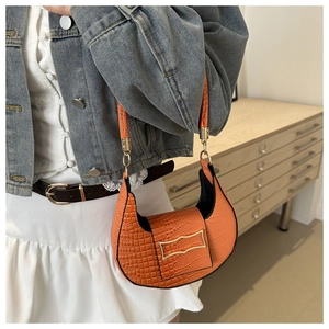 Détail du sac croissant orange en cuir à motif crocodile et boucle métallique dorée chic