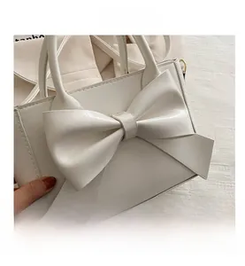 Detailed macro view of white PU leather handbag featuring a large decorative bow
