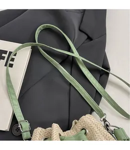 Macro detail of beige straw bucket bag featuring mint green leather strap and gold metal clasp