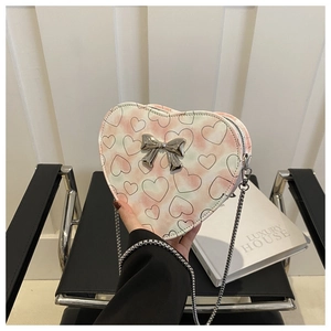 Detailed shot of a heart-shaped crossbody bag with pink heart pattern and metal bow