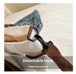 Detail view of the detachable black hook on the off-white canvas tote bag strap