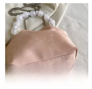Dettagli della borsa scamosciata rosa con manico di perle bianche e catena metallica