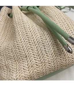 Detailed macro view of woven straw bucket bag with green leather drawstring and silver metal tips