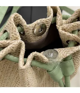 Close-up of silver magnetic clasp on straw bucket bag with green leather drawstrings