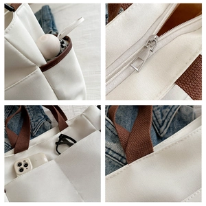 Detailed view of white canvas tote bag with brown straps and functional pockets
