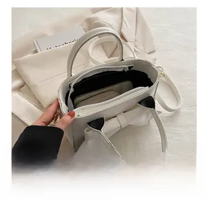 Detail view of white leather handbag interior showing a black lining and zip compartment