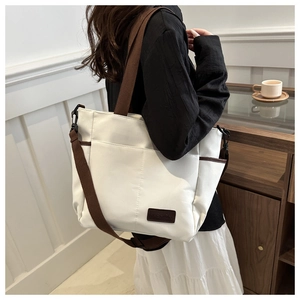 Detail view of large canvas tote bag showing fashion leather tag and side pocket