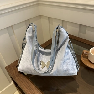 Borsa a tracolla azzurra a pieghe con fibbia a farfalla argentata in un caffè