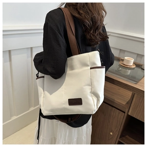 Detailed view of cream canvas tote bag featuring brown woven handles and fashion label
