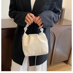 Dettaglio borsa a nuvola plissettata beige con grandi perle e tracolla a catena sottile