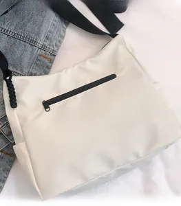 Détail de la poche arrière zippée et des poches latérales sur le sac cabas en nylon blanc