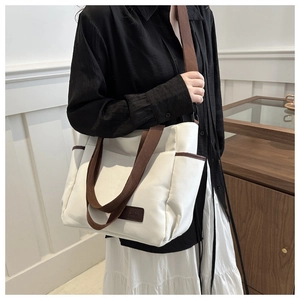 Detail view of canvas tote bag with side pockets and a fashion leather patch on the front