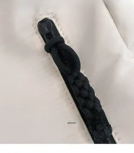 Gros plan d'une tirette de fermeture en corde tressée noire sur un sac cabas en nylon blanc