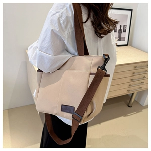 Detail of canvas tote bag with brown straps and fashion label in casual home setting