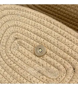 Close-up of golden metallic magnetic closure on woven straw beach shoulder bag