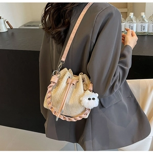 Detail view of woven straw bucket bag with pink leather strap and cute plush charm pendant