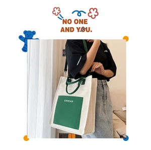 Detail of canvas tote bag with green front pocket, JINNIAN logo and durable carry straps