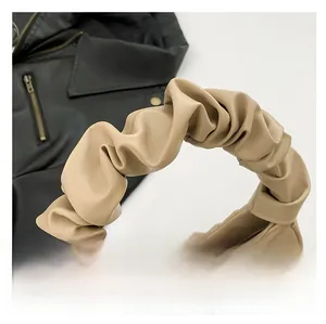 Detail of beige pleated cloud bag with pink butterfly motif and ruched top handle